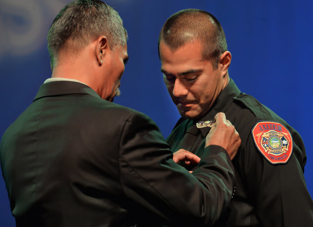 Anaheim Firefighter Carlos Torres receives his badge from his father Jose Torres during the Anaheim Fire & Rescue Promotion and Graduation ceremony. Photo by Steven Georges/Behind the Badge OC