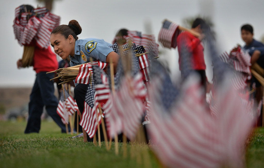 Anaheim PD Explorer Estefania Acosta, 16, helps jr. cadets in placing American flags in gravesites for Memorial Day, part of A Flag for Every Hero, at Riverside National Cemetery. Photo by Steven Georges/Behind the Badge OC