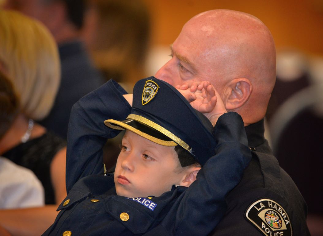 Six-year-old Samuel Principe sits in his dad’s lap, Officer Phil Principe, during La Habra PD’s Awards & Commendations Ceremony. Samuel’s father was present to receive the Lifesaving Medal and Career Service Medal for 25 years. Photo by Steven Georges/Behind the Badge OC
