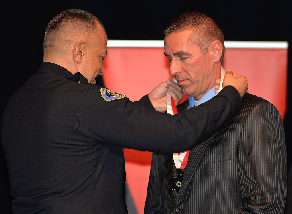 Officer Ken Johnson receives a Lifesaving Medal “for quick actions and immediate lifesaving efforts that saved a 5-year-old girl’ from Anaheim Police Chief Raul Quezada during Anaheim PD’s 2015 Awards and Retirement Ceremony. Photo by Steven Georges/Behind the Badge OC