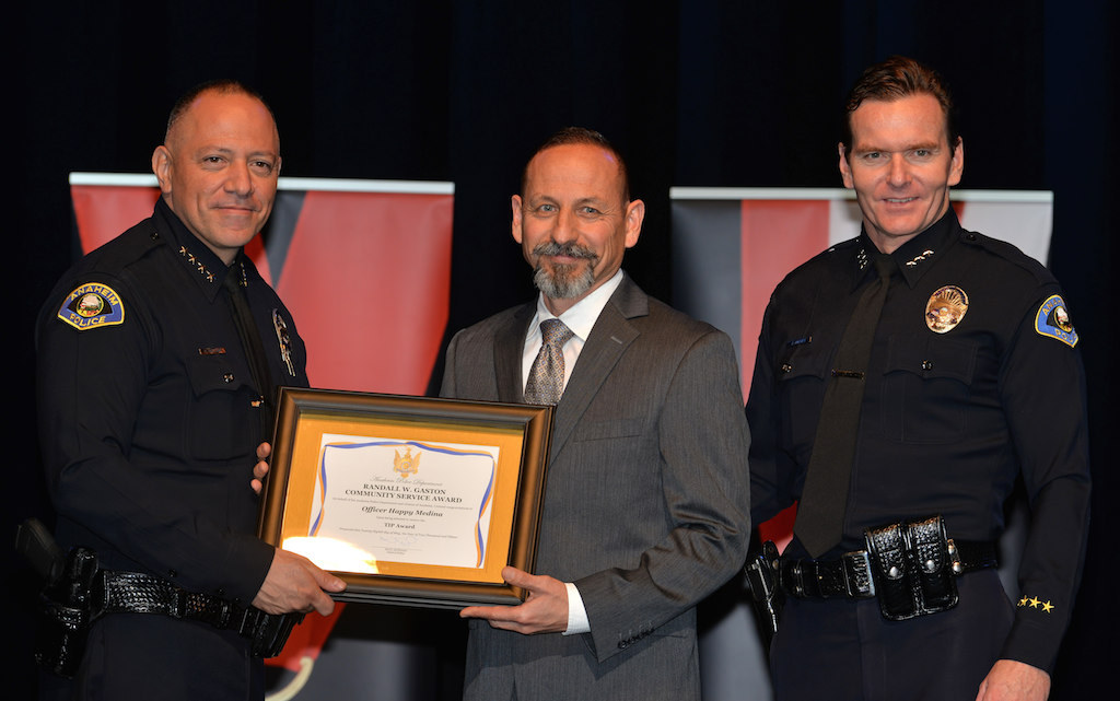 Officer Happy Medina, center, receives the TIP Officer of the Year award from Anaheim Police Chief Raul Quezada, left, and Anaheim Deputy Chief Julian Harvey during Anaheim PD’s 2015 Awards and Retirement Ceremony. Photo by Steven Georges/Behind the Badge OC