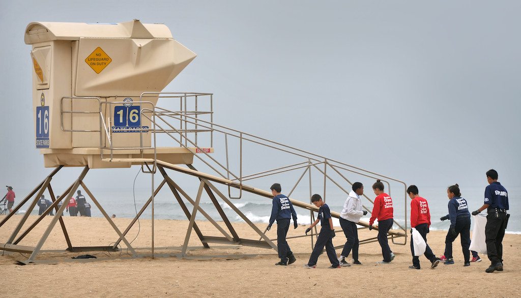 Anaheim PD junior cadets and an explorer walk by Lifeguard Tower 16 at Bolsa Chica State Beach in Huntington Beach as they hunt for trash during a beach cleanup. Photo by Steven Georges/Behind the Badge OC