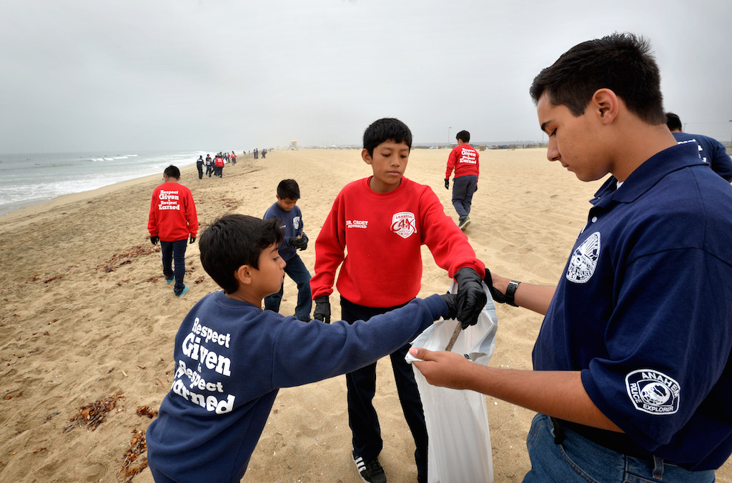 Anaheim PD Explorer Joshua Rico, right, accepts trash from junior cadets during the early morning ours of a beach cleanup at Bolsa Chica State Beach in Huntington Beach. Photo by Steven Georges/Behind the Badge OC