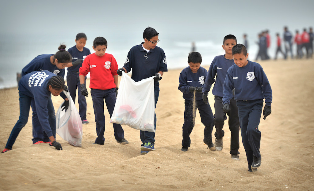 Anaheim PD junior cadets walk with an explorer as they look for trash at Bolsa Chica State Beach in Huntington Beach during a beach cleanup. Photo by Steven Georges/Behind the Badge OC