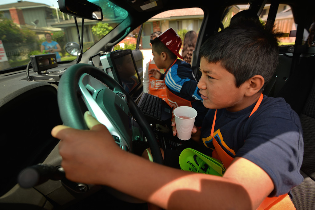 Ten-year-old Christian Felix uses his imagination to chase down bad guys as he sits behind the wheel of a Garden Grove patrol car during a community gathering along Laguna Street in Garden Grove. Photo by Steven Georges/Behind the Badge OC