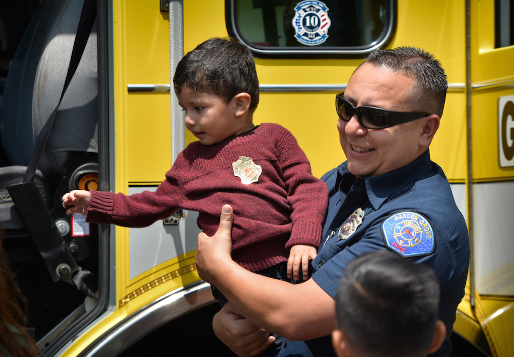 Norman Lovely, a Garden Grove fire engineer from Station 6 picks up 2-year-old Aiden Rivera to get a better look at a Garden Grove fire engine during a community gathering in Garden Grove. Photo by Steven Georges/Behind the Badge OC