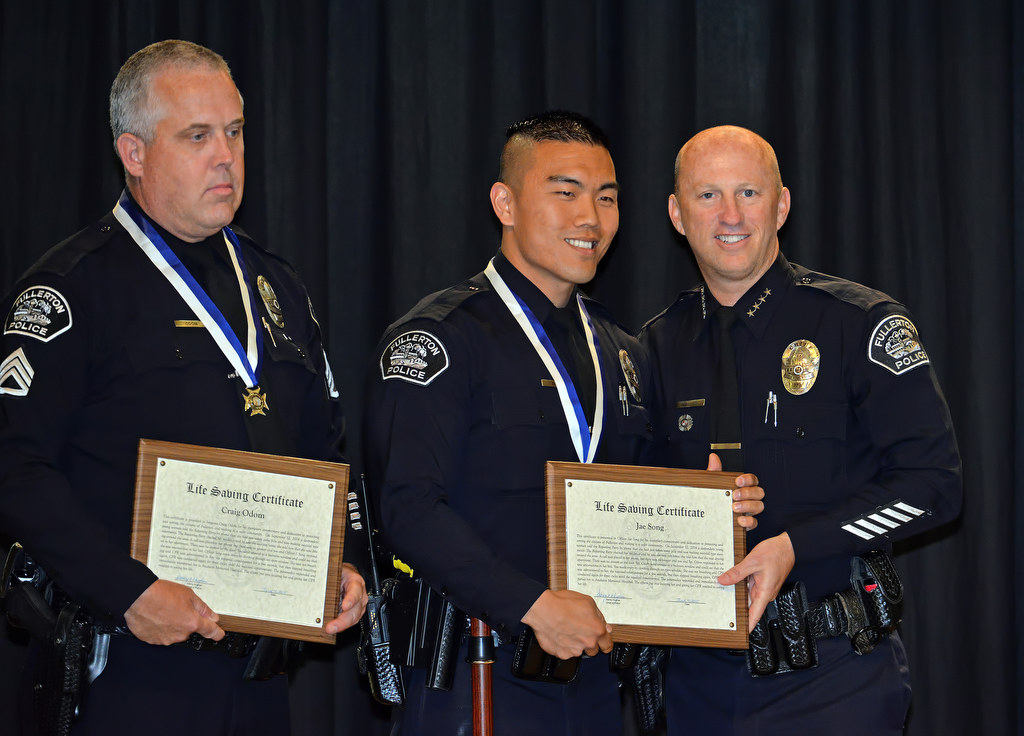Sgt. Craig Odom, left, and Officer Jae Song receive the Life Saving Medal from Chief Dan Hughes during Fullerton PD’s Promotions and Awards Ceremony for their role reviving a women who had stopped breathing. Photo by Steven Georges/Behind the Badge OC