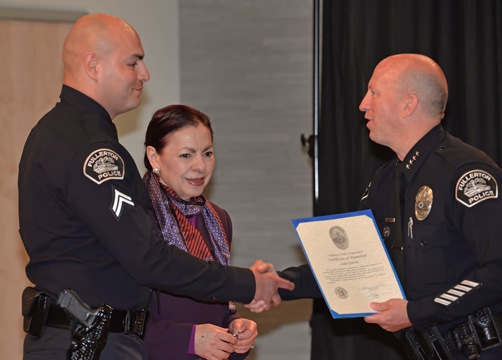 Luis Garcia receives his promotion certificate to the rank of Corporal from Chief Dan Hughes before his mother Lourdes, center, pins on his new badge during Fullerton PD’s Promotions and Awards Ceremony. Photo by Steven Georges/Behind the Badge OC