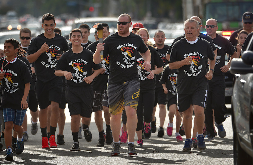 The Garden Grove PD team runs with the torch down Chapman Ave. during the Law Enforcement Torch Run for Special Olympics. Photo by Steven Georges/Behind the Badge OC