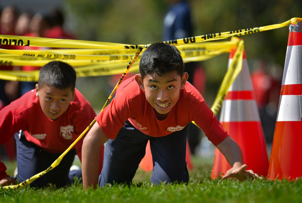 Junior cadetÕs Davidson Vu, left, and Jesus Valle crawl under police tape for an obstacle course during Anaheim PDÕs Cops 4 Kids Jr. Cadet Academy at Betsy Ross Elementary. Photo by Steven Georges/Behind the Badge OC