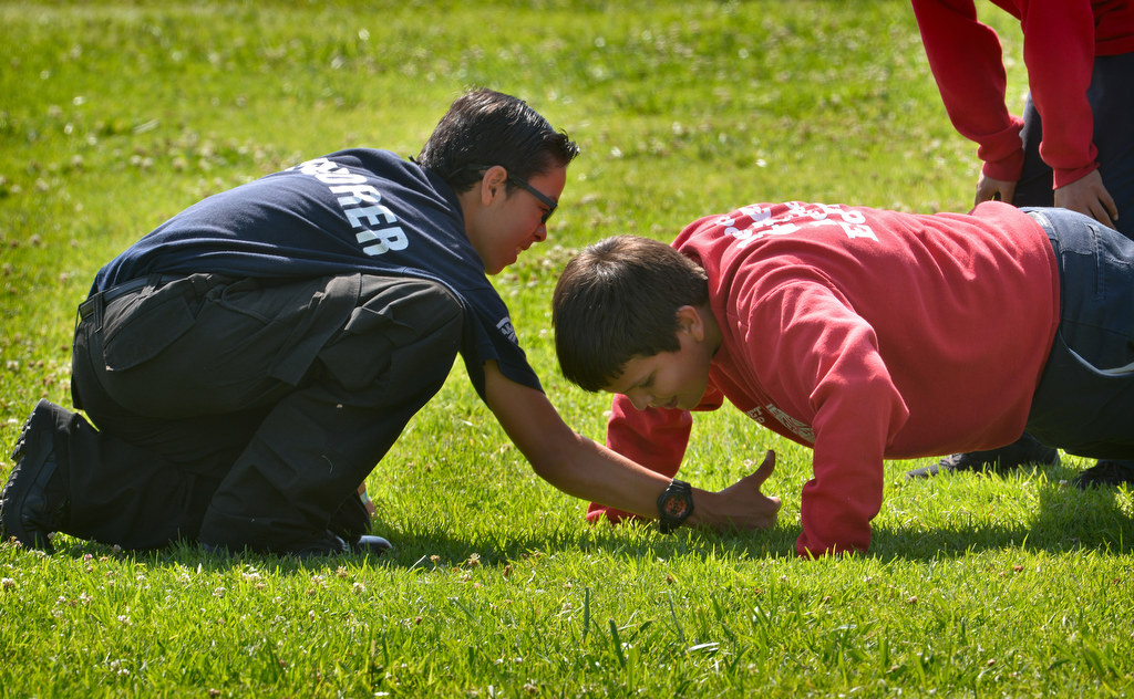 Junior cadet Alexander Herrera, right, does pushups under the supervision of Explorer Wencis Lua for an obstacle course during Anaheim PDÕs Cops 4 Kids Jr. Cadet Academy at Betsy Ross Elementary. Photo by Steven Georges/Behind the Badge OC