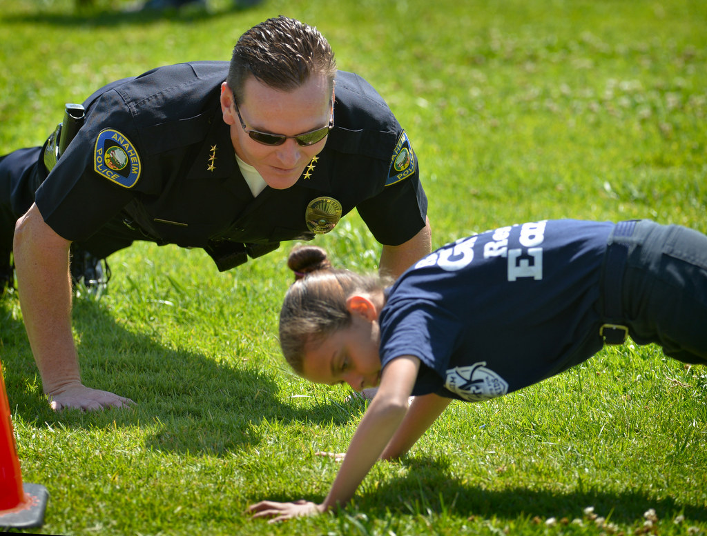 Anaheim Deputy Chief Julian Harvey joins junior cadets in a few pushups during a visit on the final day of Anaheim PDÕs Cops 4 Kids Jr. Cadet Academy at Betsy Ross Elementary. Photo by Steven Georges/Behind the Badge OC