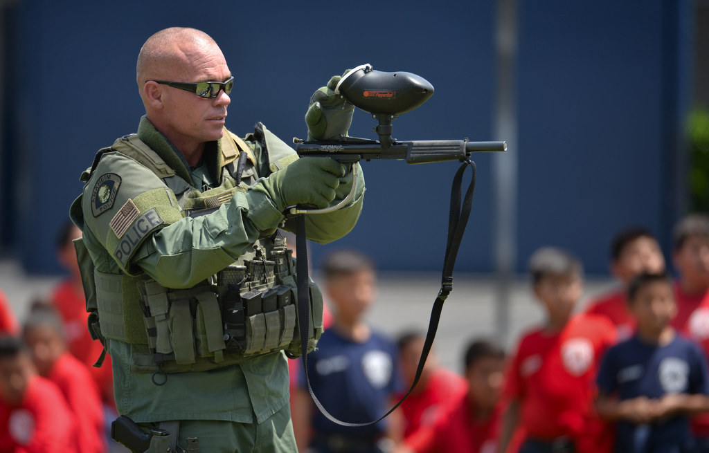 Anaheim SWAT Officer Erik Degn demonstrates various weapons including a paintball gun for junior cadets during Anaheim PD Cops 4 Kids Jr. Cadet Academy at Betsy Ross Elementary. Photo by Steven Georges/Behind the Badge OC