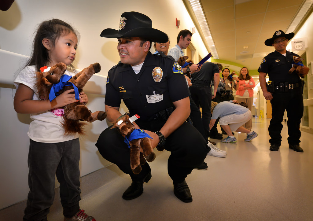Anaheim Police Officer Jose Duran gives Anabel Garcia, almost 3, an Anaheim Police Mounted Unit toy horse in the hallways of CHOC. Photo by Steven Georges/Behind the Badge OC