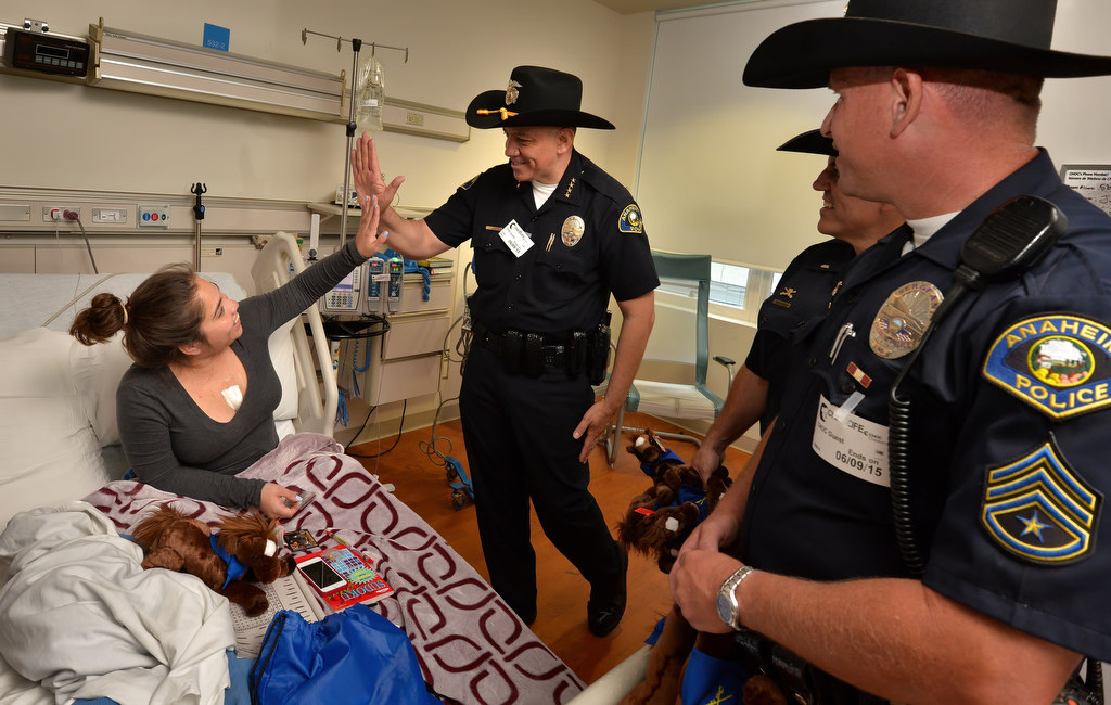 Daisy Alamzan, 20, gives Anaheim Police Chief Raul Quezada a high-five from her hospital bed after receiving an Anaheim Police Mounted Unit toy horse during a visit to CHOC. Photo by Steven Georges/Behind the Badge OC
