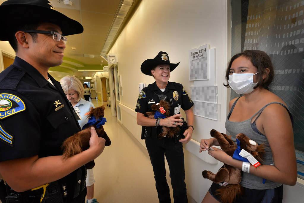 Officer Long Cao, left, and Officer Cherie Hill gives Berenice Garcia, 18, an Anaheim Police Mounted Unit toy horse while walking in the hallways of CHOC. Photo by Steven Georges/Behind the Badge OC