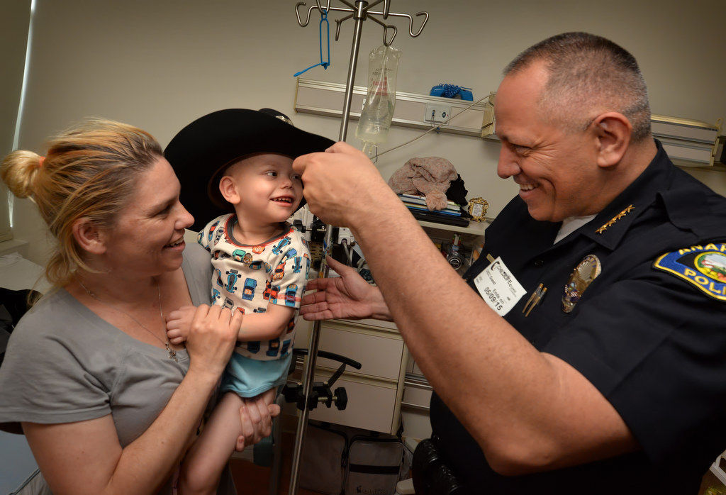 Anaheim Police Chief Raul Quezada lets 2-year-old Levi Rheuby try on his mounted unit police hat as Levi’s mother Heather Rheuby of Orange holds him as the Anaheim PD pays a visit to CHOC. Photo by Steven Georges/Behind the Badge OC