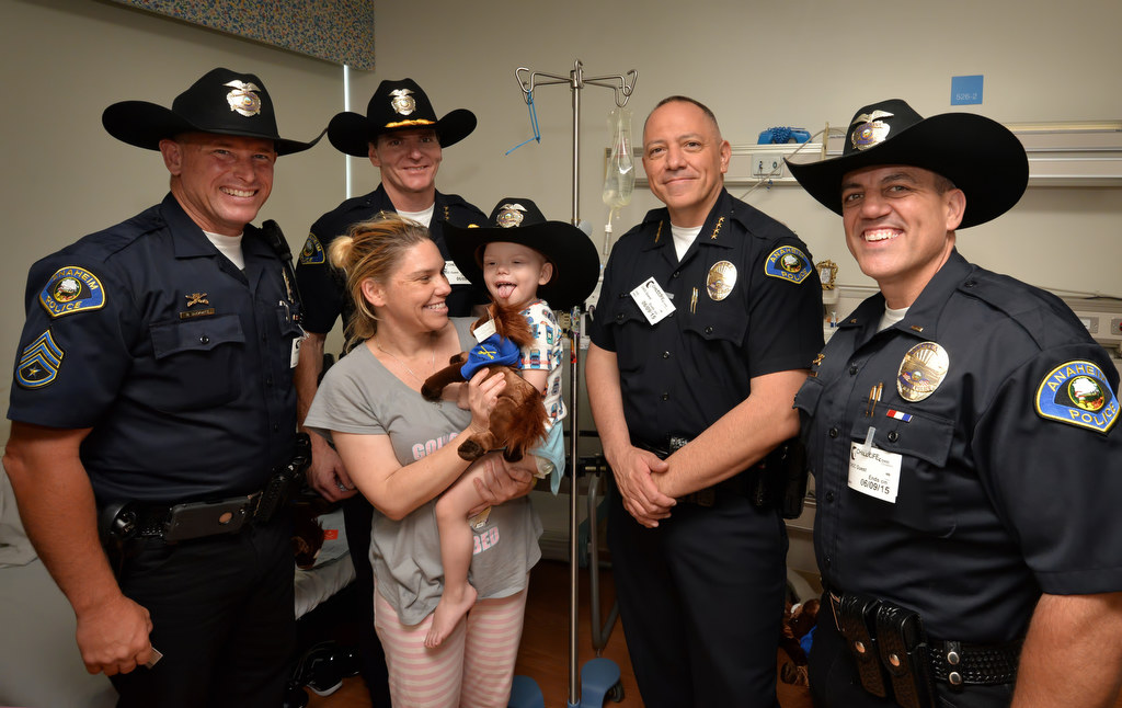 Heather Rheuby of Orange holds her 2-year-old son Levi Rheuby as Anaheim Police Sgt. Rodney Duckwitz, left, Anaheim Deputy Chief Julian Harvey, Anaheim Police Chief Raul Quezada and Lt. Richard LaRochelle pay him a visit in his hospital room at CHOC. Photo by Steven Georges/Behind the Badge OC