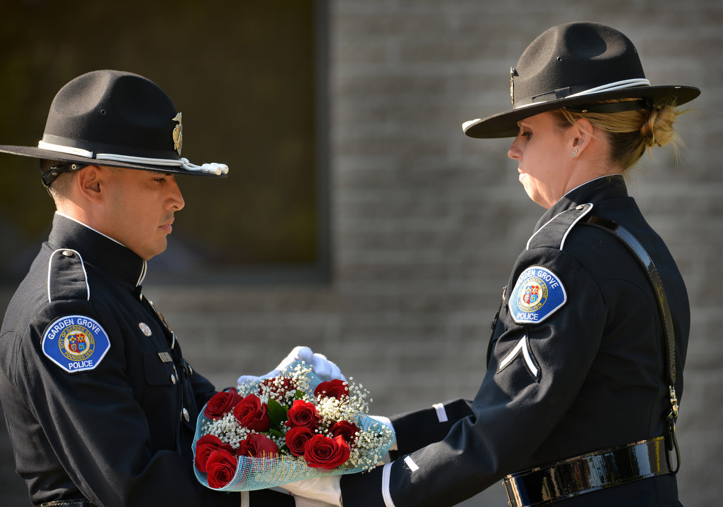 Detective Dennis Wardle, left, and Detective Lea Kovacs present flowers to one of the families of fallen officers during Garden Grove PDÕs 28th Annual ÒCall to DutyÓ Memorial Service. Officers presented flowers to each of the attending families of fallen Garden Grove officers. Photo by Steven Georges/Behind the Badge OC