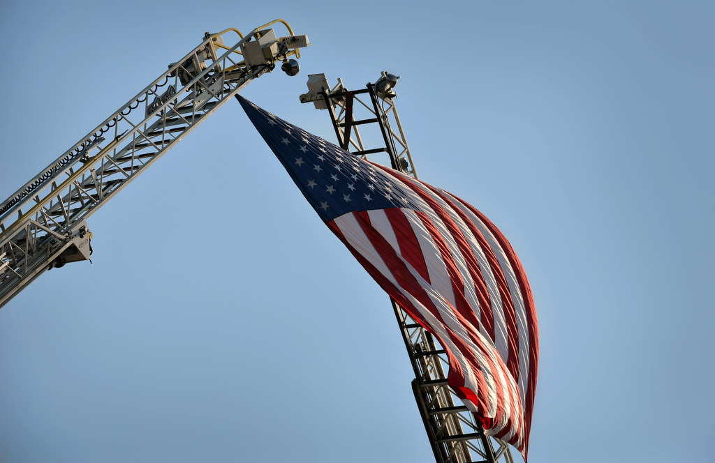 A flag is draped from the ladders of two Garden Grove Fire Trucks during Garden Grove PD’s 28th Annual “Call to Duty” Memorial Service. Photo by Steven Georges/Behind the Badge OC