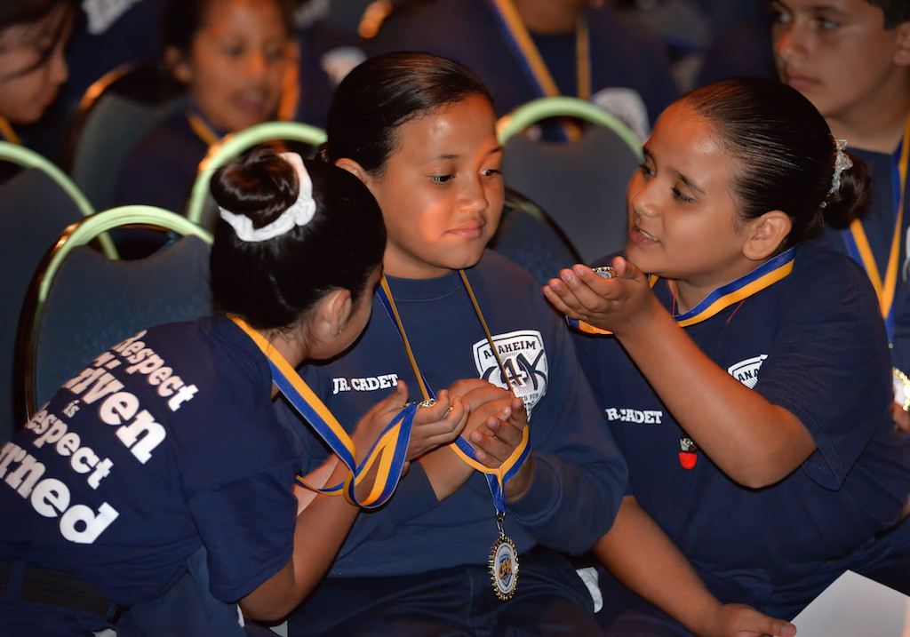 Jr. Cadets Paola Ferreyra, 8, left, Fisher Chanel, 10, and Flores Camila, 10, examine the graduation medals they received during Anaheim PD’s Jr. Cadet Graduation Ceremony. Photo by Steven Georges/Behind the Badge OC
