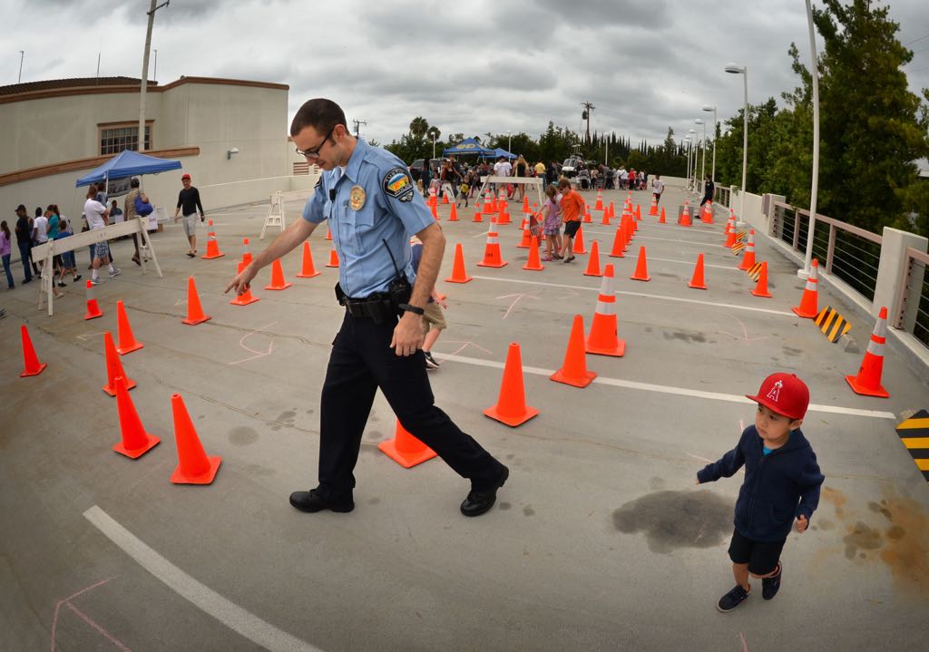 Tustin Parking Control Officer Garrett Georgians helps 4-year-old Tyler Do of Tustin run through the Bike Safety Course during Tustin PD’s 19th Annual Open House. Photo by Steven Georges/Behind the Badge OC
