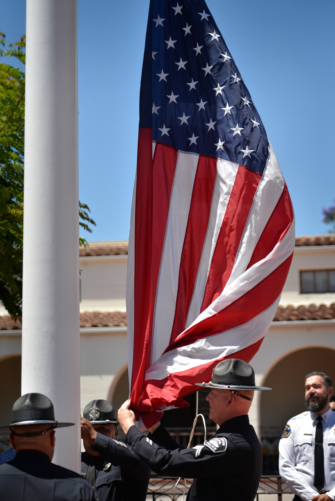 Fullerton Police Officer Miguel “Sonny” Siliceo, left, Officer Richie Herrera and Cpl. Scott Moore rase the flag during a memorial ceremony in front of the Fullerton Police Department honoring fallen Fullerton Police Officer Tommy De La Rosa who was killed in the line of duty on June 21, 1990. Photo by Steven Georges/Behind the Badge OC