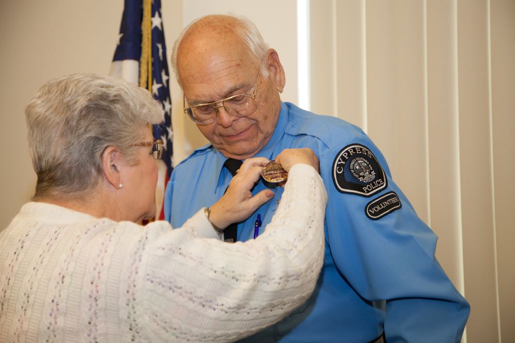 Wayne Schoemann gets a badge pinned from his wife. Schoemann is the first Cypress Police volunteer to log 4,000 hours. Photo courtesy Cypress PD. 
