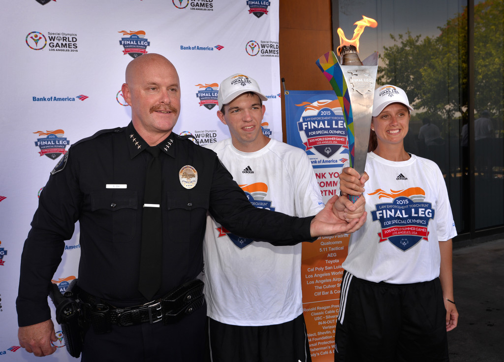 Cypress Police Chief Rod Cox, left, gets a chance to hold the Special Olympic torch with Special Olympic Athlete Cody Pierce and Trisha Doranilla, a police officer in Honolulu Hawaii, after the Law Enforcement Torch Run Final Leg for Special Olympics runners arrived in Cypress. Photo by Steven Georges/Behind the Badge OC