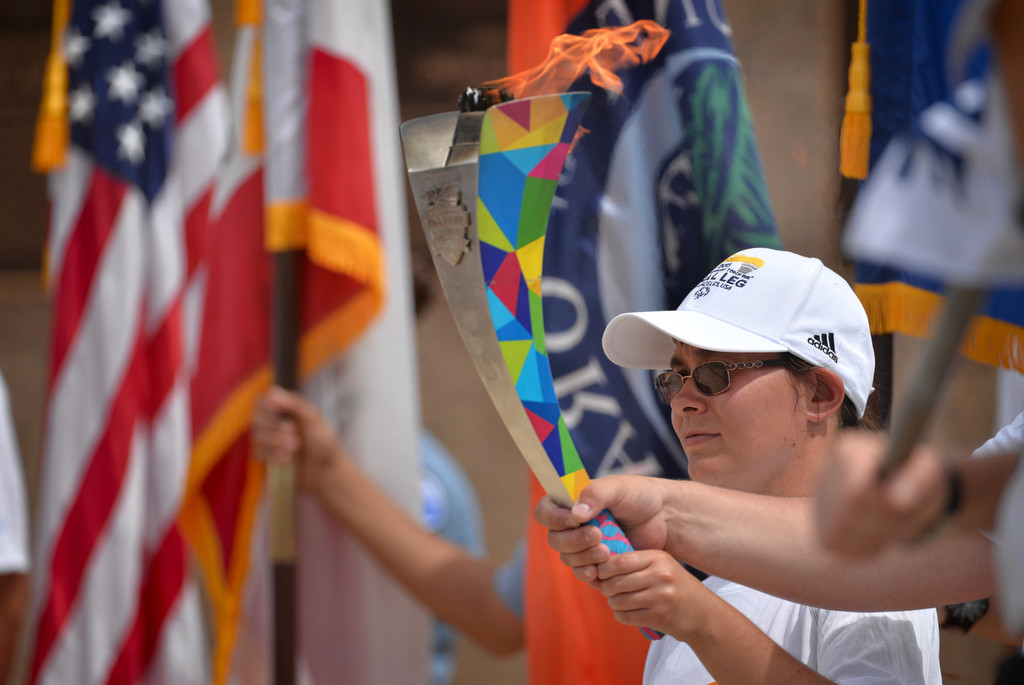 Special Olympic Athlete Daniela Brandt holds up the Special Olympics torch with the American, California, Orange County and Garden Grove flags, respectively, behind her during a ceremony at the Garden Grove PD. Photo by Steven Georges/Behind the Badge OC