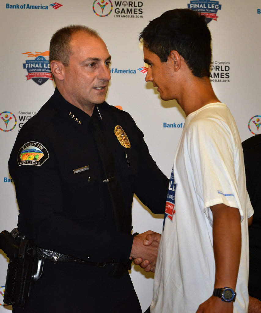 Tustin Police Chief Charles Celano greets Special Olympic Athlete Brett Laza on stage during a torch run ceremony in Tustin. Photo by Steven Georges/Behind the Badge OC