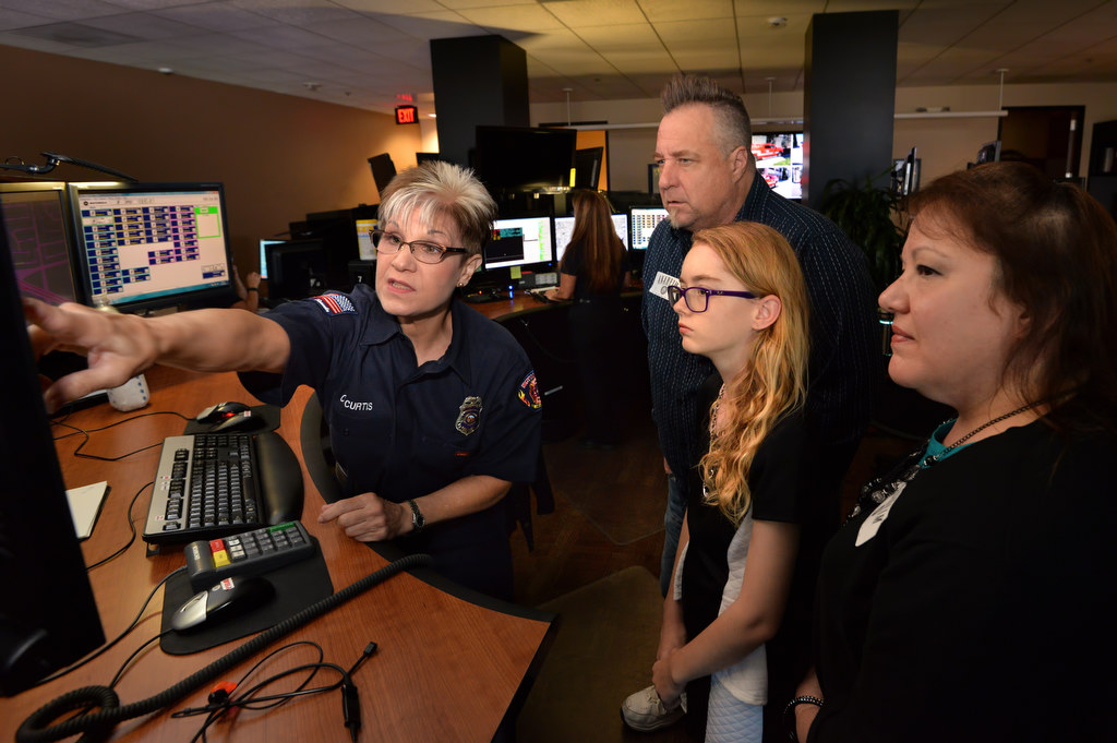Cheryl Curtis, a Fire Dispatcher II from Anaheim Fire & Rescue, left, gives 12-year-old Angela Chute, her father William Chute and mother Bernadette Chute a tour of the 911 operations during a visit to AF&R headquarters. Curtis was the 911 dispatcher that took the call from Angela when her father had a seizure. Photo by Steven Georges/Behind the Badge OC