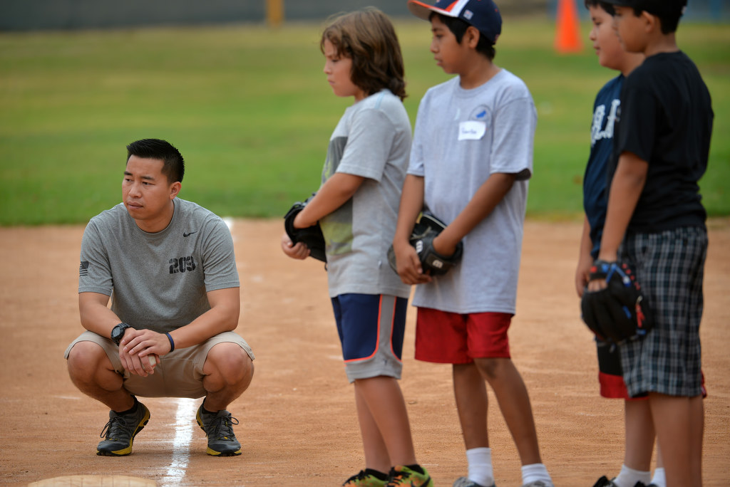 Fullerton Police Cpl. Billy Phu works with kids during an at-risk baseball camp in Fullerton. Next to him are Misael Flores, 9, Ricardo Vasquez, 11, Juan Ugalde, 10, and Jorge Galvan, 10. Photo by Steven Georges/Behind the Badge OC