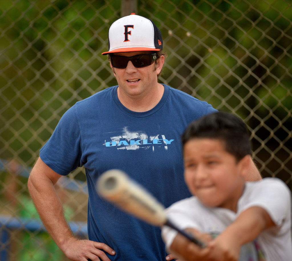 Fullerton PD officer xxxx keeps an eye on Justin Rodriguez, 12, as he gets his turn at bat during a baseball camp for at-risk kids at "The YardÓ in Fullerton. Photo by Steven Georges/Behind the Badge OC