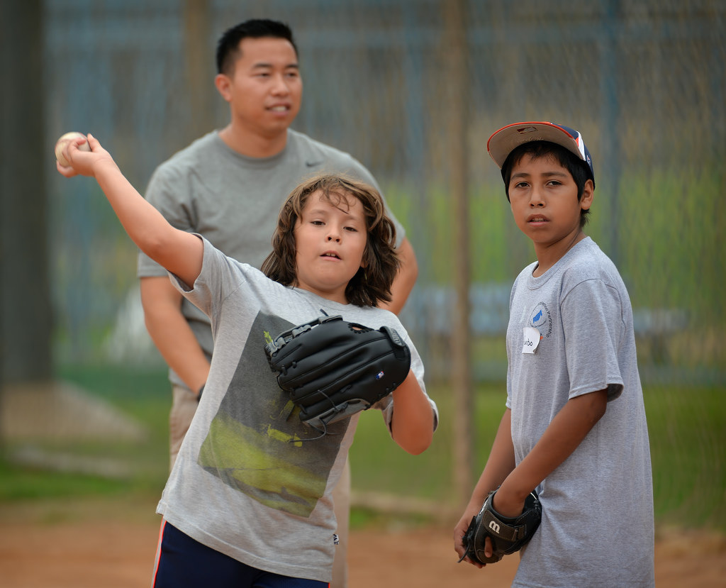 Misael Flores, 9, left, and Ricardo Vasquez,11, run through drills with Fullerton Police Cpl. Billy Phu behind them during an at-risk baseball camp in Fullerton. Photo by Steven Georges/Behind the Badge OC