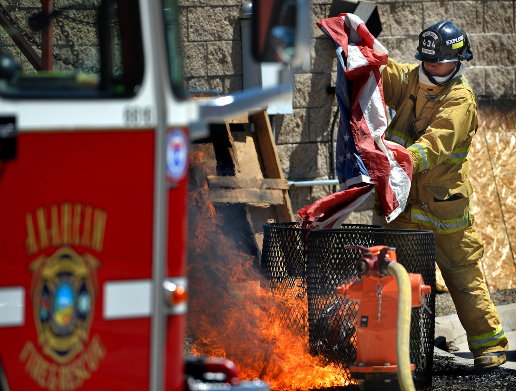 Anaheim Fire & Rescue Explorer Adrian Montanez places a flag in the fire during a flag burning ceremony as approximately 430 flags were retired at the North Net Fire Training Center in Anaheim. Photo by Steven Georges/Behind the Badge OC