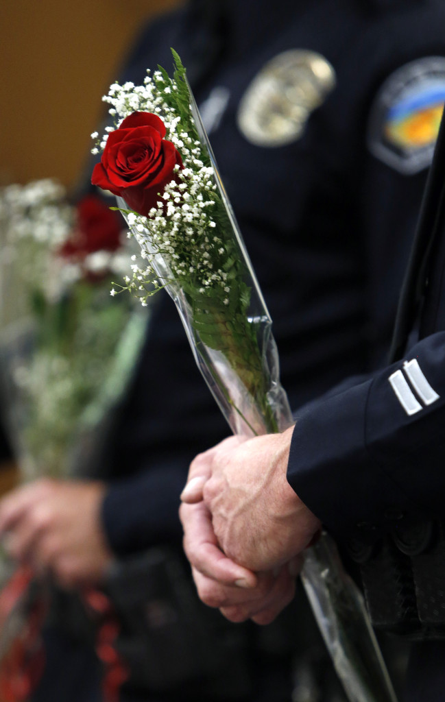 Tustin police officers John Hedges and David Welde hold roses presented to them by Kelli Capone after her graduation from a drug and alcohol rehab program. The two officers were instrumental in her recovery.   Photo by Christine Cotter/Behind the Badge OC