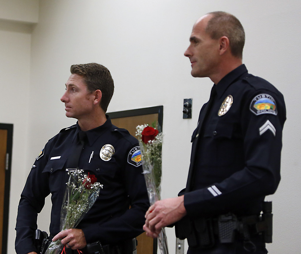 Tustin police officers John Hedges and David Welde, from left, hold roses presented to them by Kelli Capone after her graduation from a  drug and alcohol rehab program. The two officers were instrumental in getting her into the program.     Photo by Christine Cotter/Behind the Badge OC