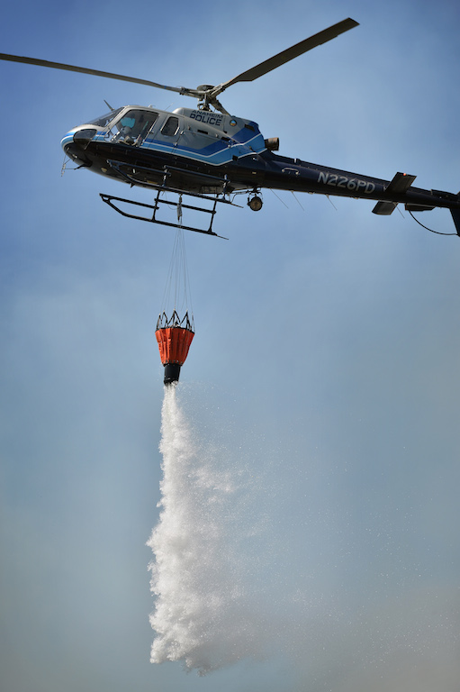 The Anaheim PD’s “Angel” helicopter drops water on a vegetation fire that broke out in the Brea Dam Recreation Area Saturday afternoon threatening homes in the Fullerton area. Photo by Steven Georges/Behind the Badge OC
