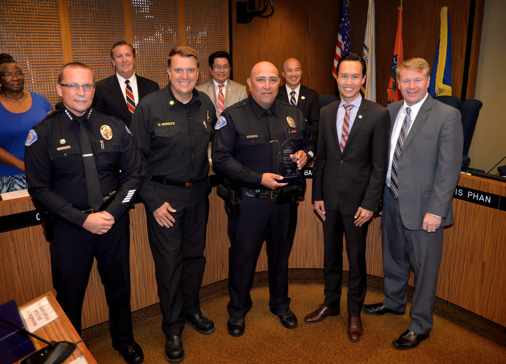 Garden Grove PD Officer Dan Villegas, center, is recognized by the Garden Grove City Council for "his heroic action saving a five month old baby by performing CPR,Ó as he receives the Community Spotlight award. Front row left is Garden Grove Police Chief Todd Elgin, Garden Grove Fire Chief Tom Schultz, Officer Dan Villegas, Garden Grove Mayor Bao Nguyen and Garden Grove Mayor Pro Tem Steve Jones. Photo by Steven Georges/Behind the Badge OC