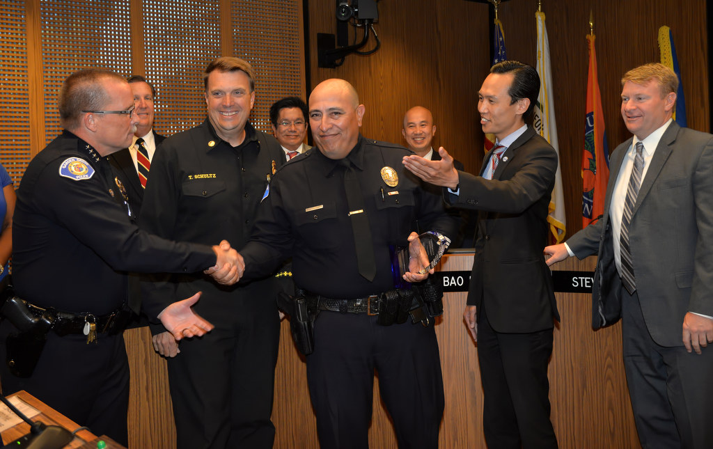 Garden Grove PD Officer Dan Villegas, center, is recognized by the Garden Grove City Council for "his heroic action saving a five month old baby by performing CPR,Ó as he receives the Community Spotlight award. Front row left is Garden Grove Police Chief Todd Elgin, Garden Grove Fire Chief Tom Schultz, Officer Dan Villegas, Garden Grove Mayor Bao Nguyen and Garden Grove Mayor Pro Tem Steve Jones. Photo by Steven Georges/Behind the Badge OC