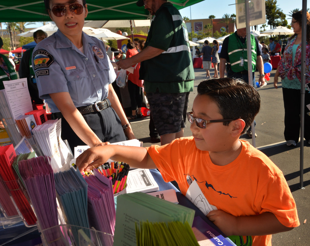 Tustin Police Volunteer Lili Golden talks to 6-year-old William Alvarado of Tustin as he checks out the pamphlets and pencils at the Tustin Police booth during National Night Out at the Target Shopping Center in Tustin. Photo by Steven Georges/Behind the Badge OC