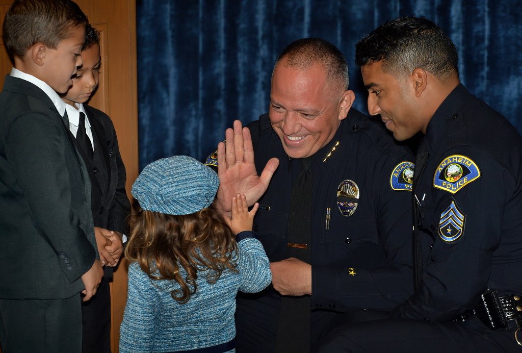 Anaheim Police Chief Raul Quezada gets a high-five from 3-year-old Samantha as her father Jonathan Bailey, left, receives a promotion to sergeant during a promotional ceremony. His two sons Owen, 6, left, and Logan, 5, helped with the pinning of the badge. Photo by Steven Georges/Behind the Badge OC