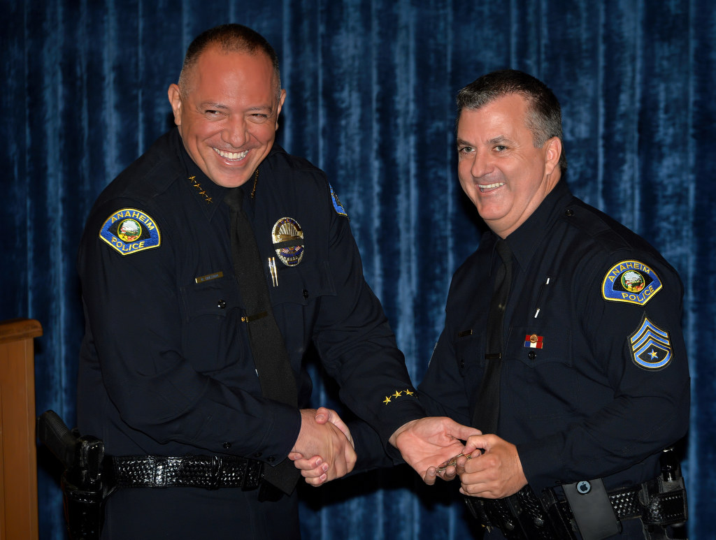 Anaheim Police Chief Raul Quezada, left, hands Kelly Phillips his new sergeant badge during a promotional ceremony at Anaheim PD headquarters. Photo by Steven Georges/Behind the Badge OC