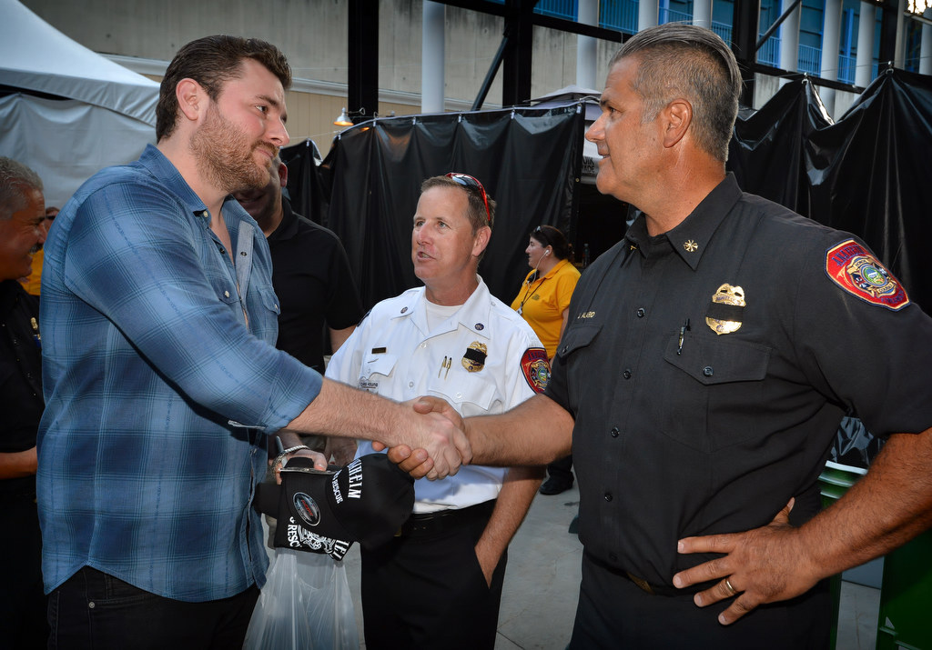 Country singer Chris Young, left, meets backstage before his concert Thursday at the Pacific Amphitheater with Anaheim Fire Marshal Jeff Lutz and Anaheim Fire & Rescue Deputy Chief Jeff Alario, right, as Young participates in a program to donate hundreds of smoke alarms to Anaheim and Costa Mesa. Photo by Steven Georges/Behind the Badge OC
