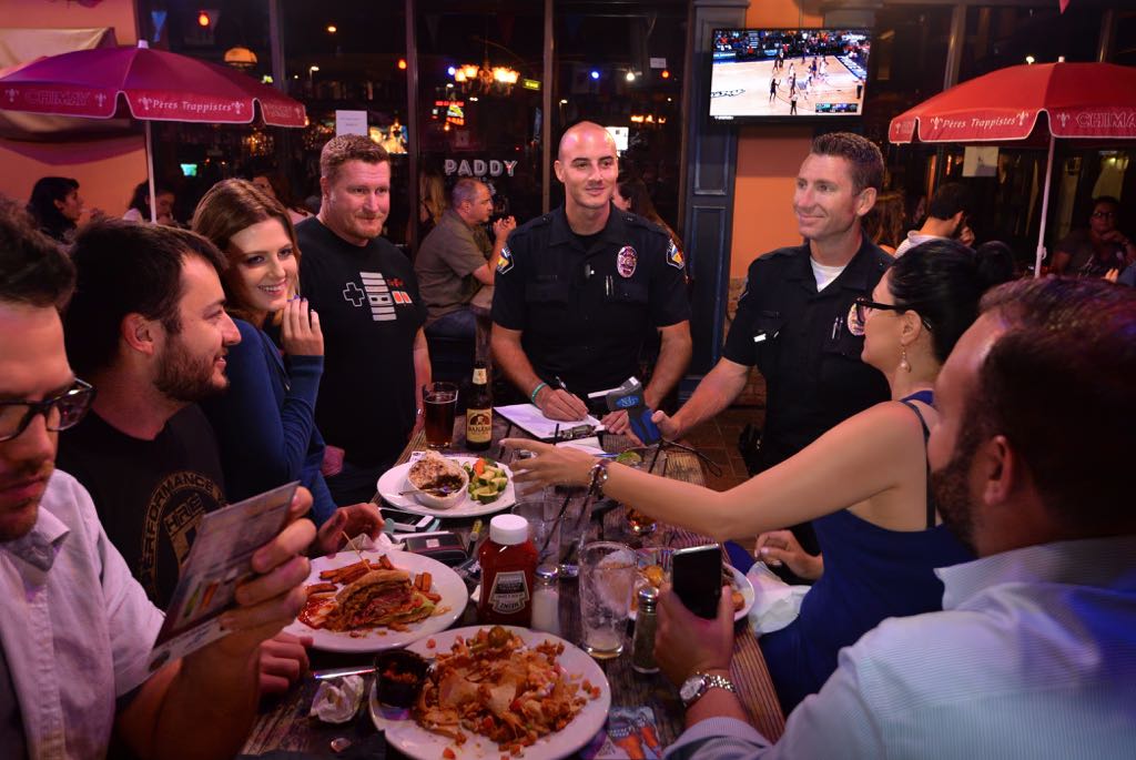 Tustin PD Officers Kyle Hurd, left, and John Hedges talks to a group of people at Auld Dubliner in Tustin about the effects of drinking and driving, part of the Know Your Limits outreach program. Photo by Steven Georges/Behind the Badge OC