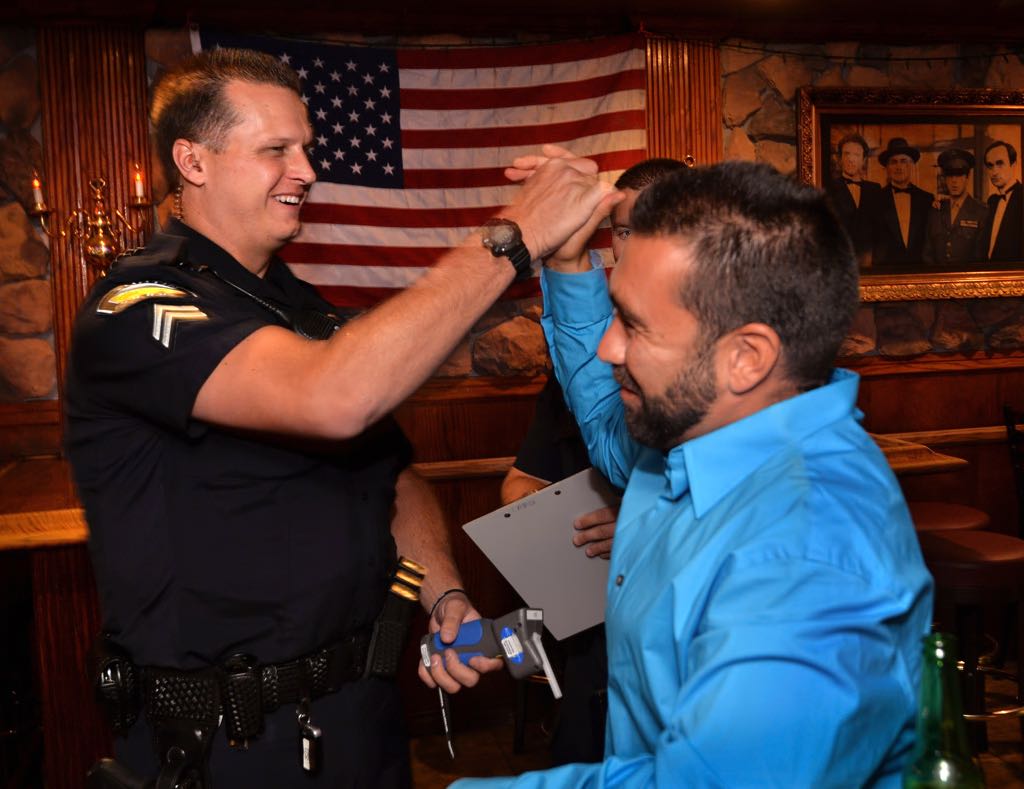 Brett Simoes of Tustin gives Tustin PD Officer Jeremy Laurich a high-five after correctly predicting that his breath test would result in a 0.08% blood alcohol level after drinking 4 bears and 2 shots of Jack Daniel's. Tustin police visited local bars to give the voluntary test as part of the Know Your Limits program to educate people about mixing drinking with driving. Photo by Steven Georges/Behind the Badge OC