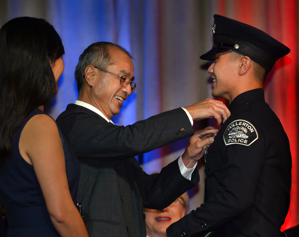 Fullerton’s new officer Christopher Chiu gets his badge pinned to him by his mother Phoebe and father Su during the OCSRTA class of 216’s graduation ceremony. Photo by Steven Georges/Behind the Badge OC