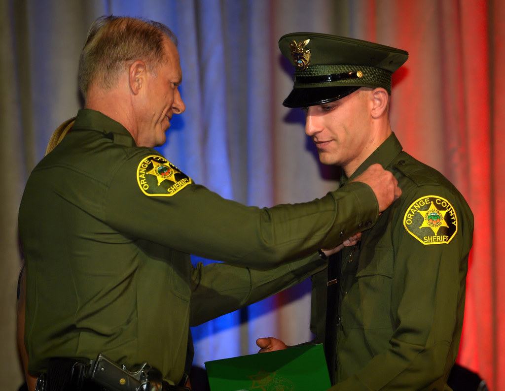 Orange County Deputy Ryan Fowler gets his new badge pinned to him by his father Brad, an investigator for the Orange County Sheriff’s Department, during the OCSRTA class of 216’s graduation ceremony. Photo by Steven Georges/Behind the Badge OC