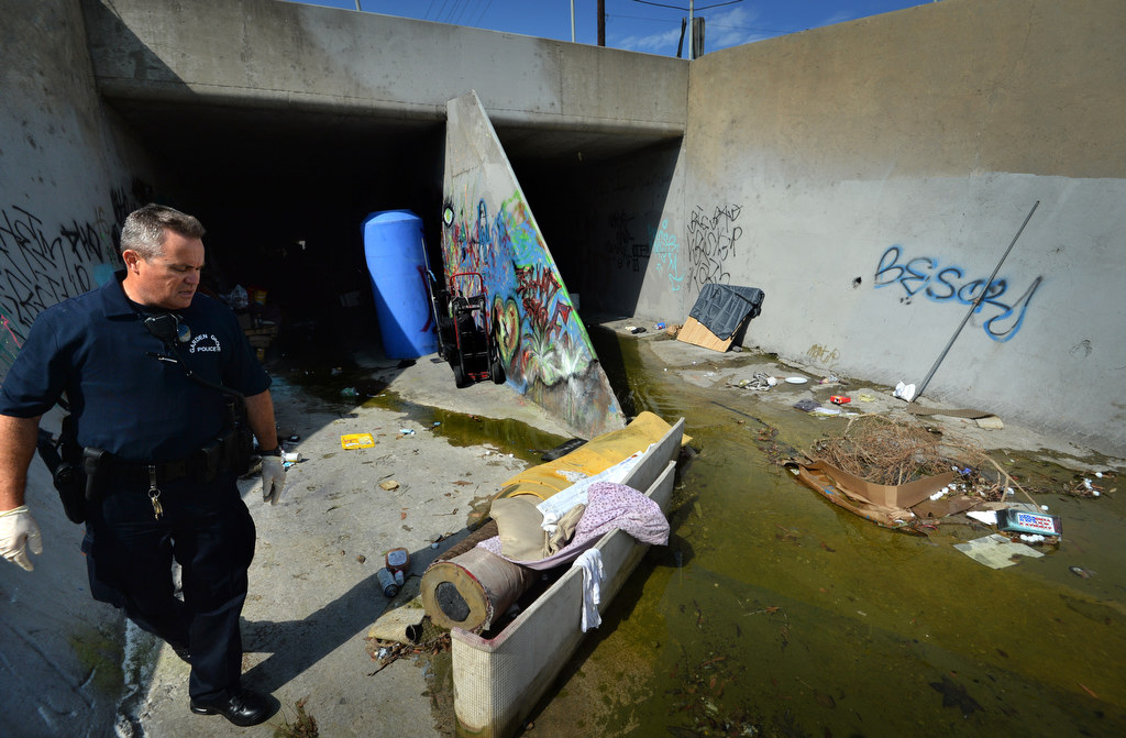 Garden Grove PD Officer Roger Flanders walks past a makeshift damn in an attempt to get the water to divert to the other side of the flood canal under Knott St. from where the homeless were living. Photo by Steven Georges/Behind the Badge OC